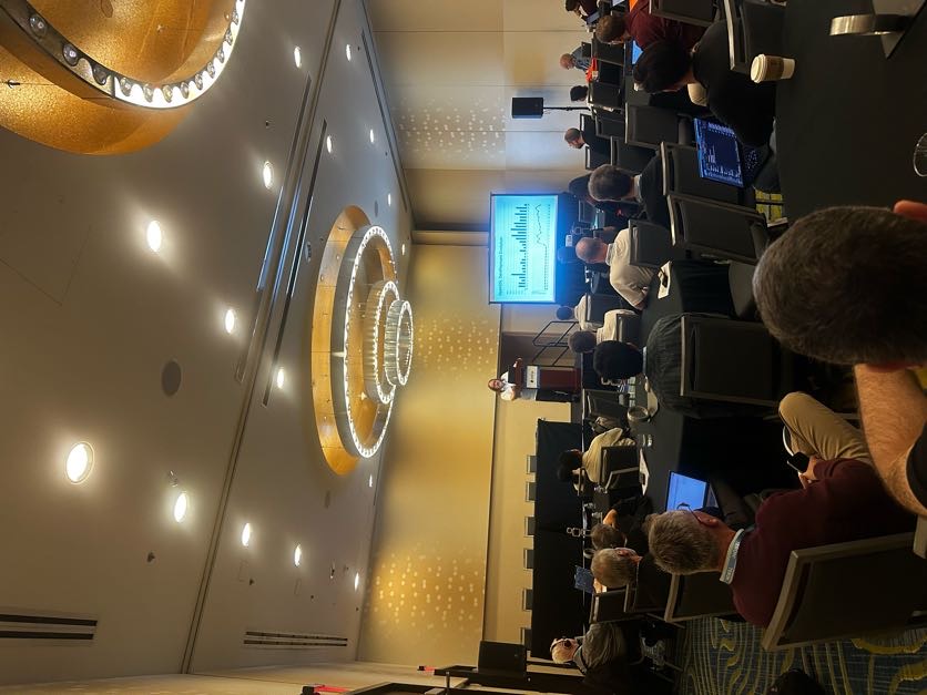 Tim Hudson at the podium in Studio E, the OpenSSL Development Evolution chart projected behind him, the room full of laptops.